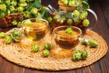 Hop Tea with Fresh Hops in Glass Cups and Teapot on Rustic Background
