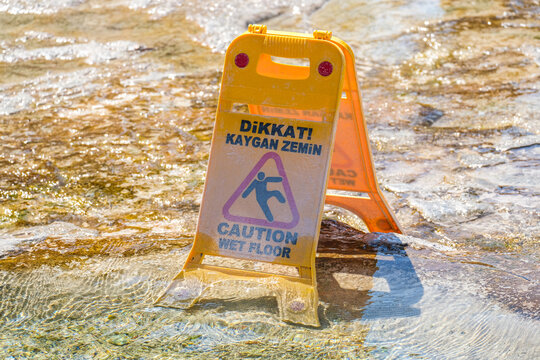Yellow wet floor sign on a wet stone surface with turkey text. Safety warning for slippery conditions display at a travel destination.