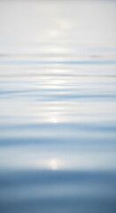 Blurred image of calm water surface, showing subtle light reflections and gentle waves, conveying serenity and tranquility, ideal for peaceful or minimalist designs