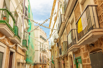 Fototapeta premium Traditional stone residential building with green balconies and palms in Cadiz, Andalusia, Spain, September 2025.