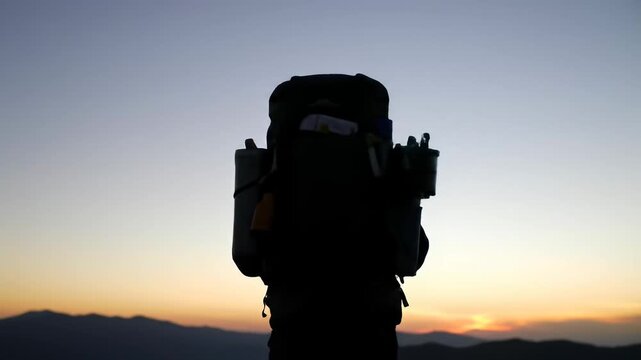 A lone hiker's silhouette against a vibrant sunset sky, standing on a mountain peak, embracing the solitude and freedom of the journey