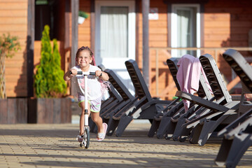 Girl riding scooter in a sunny courtyard