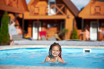 Obraz premium Joyful girl swimming in pool at resort