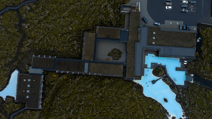 The Blue Lagoon's milky blue waters contrast with dark volcanic terrain, featuring modern...
