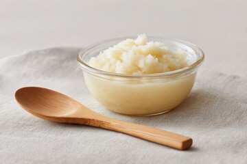 A Bowl of Creamy White Substance with a Wooden Spoon on a Textured Surface, Featuring a Smooth Texture and Soft Appearance for Culinary Use
