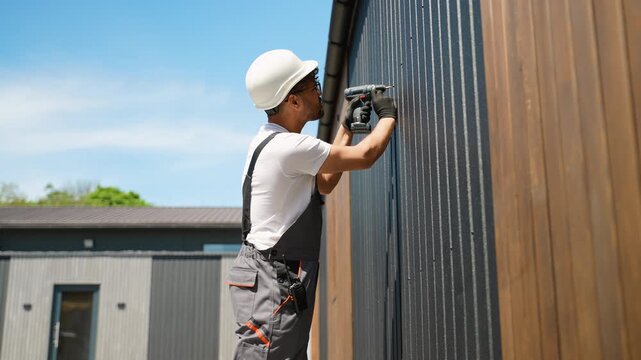 Construction worker installing siding on building exterior