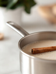 Cozy beverage preparation: Milk simmering in a saucepan with a cinnamon stick, creating a warm, comforting drink.