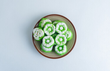 A plate full of Indonesian traditional snack putu ayu, green pandan steamed cakes topped with shredded coconut, ready to serve.