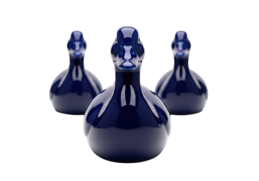 Sleek indigo blue porcelain duck, two smaller ones in a precise triangle, on transparent with copy space, soft shadows, high-key studio light, minimalist elegance concept