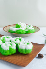 Freshly made Indonesian steamed cakes putu ayu with coconut topping placed on a wooden table, traditional homemade snack.