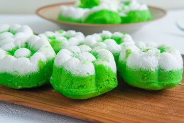 Macro close-up of Indonesian putu ayu cake showing soft green pandan base and grated coconut topping in detail.