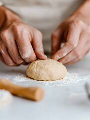 Dough Preparation: Close-up of hands kneading a ball of dough on a floured surface, ready for baking. Preparation in progress.