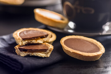 Sweet chocolate tartelettes on black table.