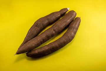 Cassava Roots (Yuca, Manihot esculenta) on Yellow Background, Edible Tropical Tuber Crop
