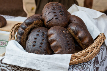 Rustic wicker basket filled with freshly baked dark rye loaves of bread in a traditional street...