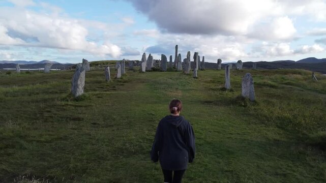 Plano a&eacute;reo siguiendo a mujer hacia el centro del c&iacute;rculo de piedras de Callanish 4K