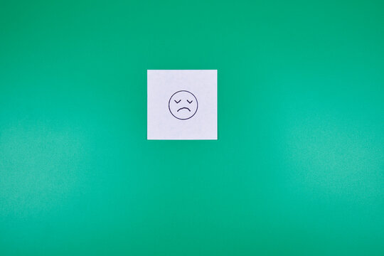 Sad emoji icon on a post-it note with a green background and copy space - Powered by Adobe
