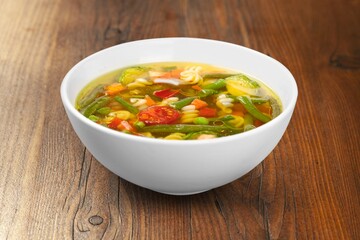Spring fresh vegetable soup in bowl on the desk