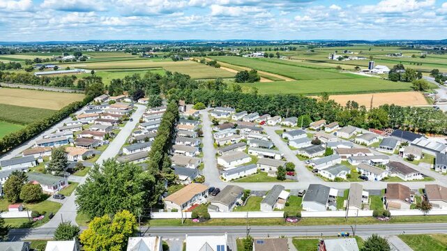 Time Lapse of a lush green fields surround a well-planned suburban mobile home community. Rows of homes are neatly lined, showcasing a peaceful lifestyle.. This landscape captures serene rural setting