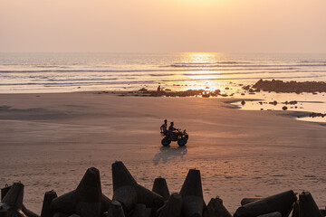Adventurous quad bike ride across glowing sands under warm golden evening light.