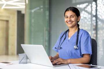 Smiling nurse working on laptop in modern hospital setting