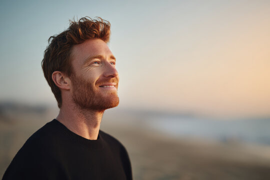man smiling with calm confidence gazing towards horizon against soft pastel background