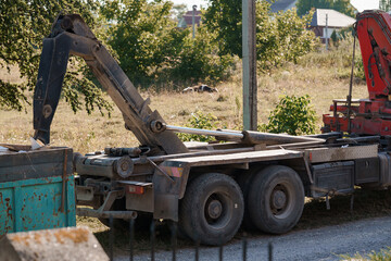 Construction Vehicle with Crane Unloading Materials on Grassy Field, Red and Green Industrial Scene