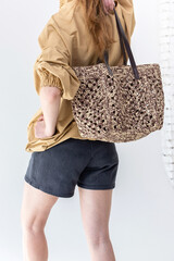 Elegant woman in beige windbreaker jacket and black shorts on light background. Fashionable female style. Studio photography. Vertical photo. Back view © lara-sh