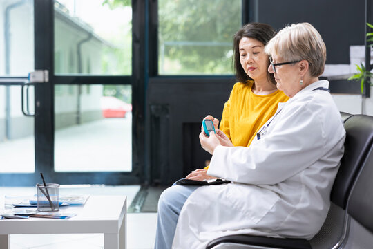 Patient receiving diabetes evaluation as medic checks sugar levels, using glucometer device in quiet medical space. Hospital staff offer guidance on monitoring and adjusting insulin dosage.