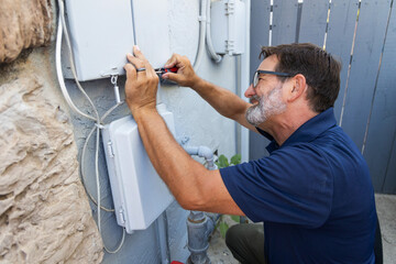 Home inspector opening an electrical panel outside a home