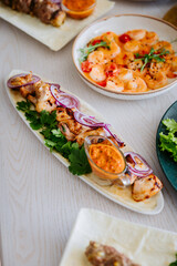 Grilled chicken kebab with red onion, cilantro and spicy sauce on a white wooden table
