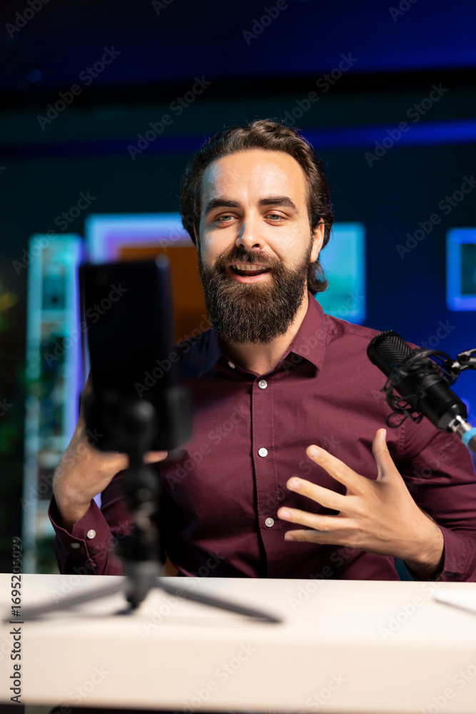 Poster online star talking in front on smartphone attached to tripod stabilizer in studio, discussing with 