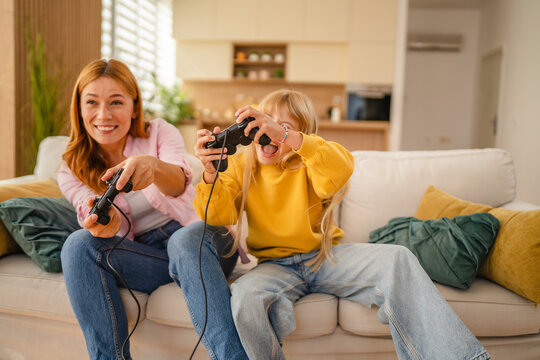 Mother and daughter having fun playing video games at home