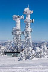 Frozen communications tower covered in thick snow and ice on a cold winter day