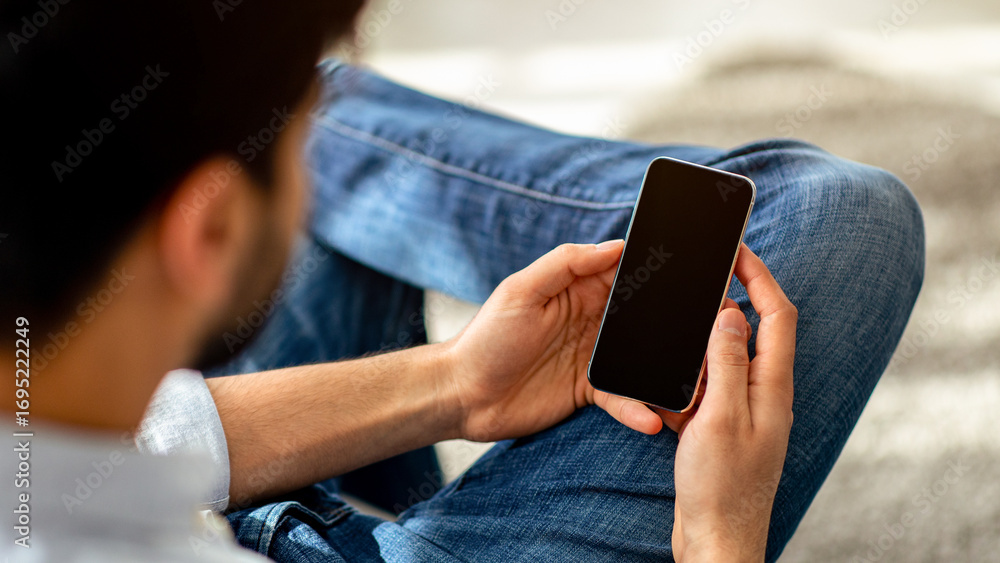 Aufkleber technology concept. over the shoulder view of unrecognizable man using cellphone with black empty sc
