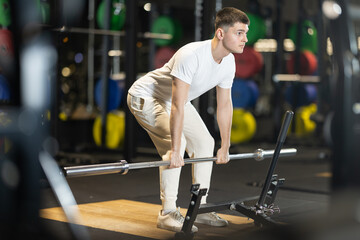 Young man executing conventional deadlift with proper stance and grip, targeting posterior chain...
