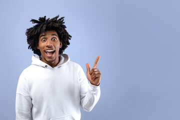 Funky black teen guy experiencing AHA moment, having creative idea, pointing up on violet studio background, copy space. Attractive African American teenager gesturing eureka