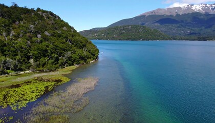 Obraz premium Aerial view of a tranquil lake surrounded by lush green hills and mountains