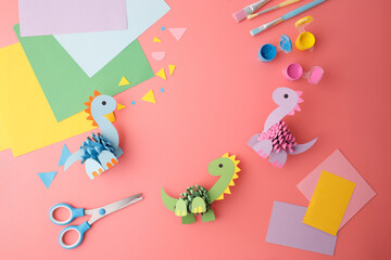 Obraz premium Colorful craft materials with painted pinecone dinosaurs on pink background. Perfect for kids workshops, DIY kit marketing, art supply stores, creative learning and seasonal craft content,