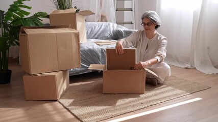 Senior woman packing picture frame into cardboard box