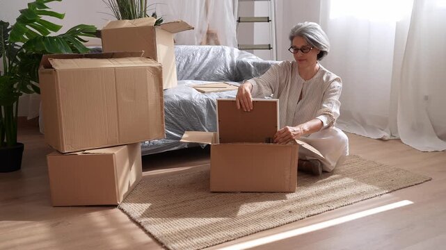 Senior woman packing picture frame into cardboard box