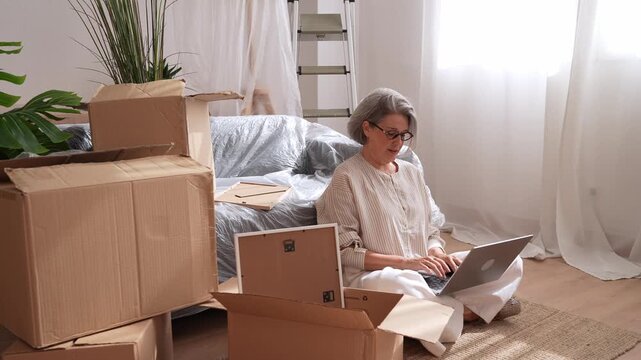 Senior woman managing relocation logistics on laptop