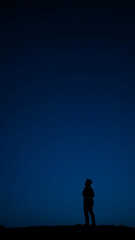 Fototapeta premium Solitary Figure in a Blue and Dark Night Sky vertical