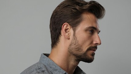 Fototapeta premium Handsome Caucasian man in plain gray background, side view looking on the right