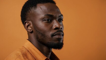 Obraz premium Handsome African man in plain orange background, side view looking on the right