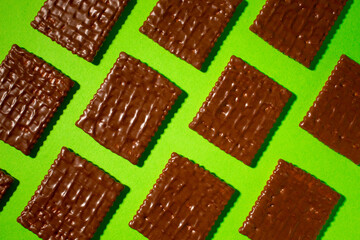 Diagonally arranged chocolate biscuit on a green background.