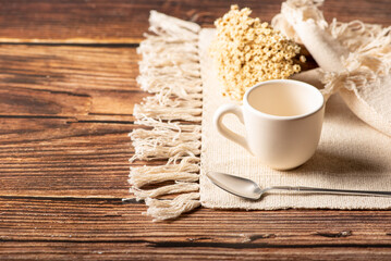 White cup, a beautiful white cup on a napkin and rustic wood surrounded by small flowers, selective focus.