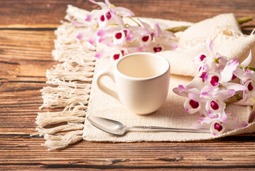 White cup, a beautiful white cup on a napkin and rustic wood surrounded by small flowers, selective focus.