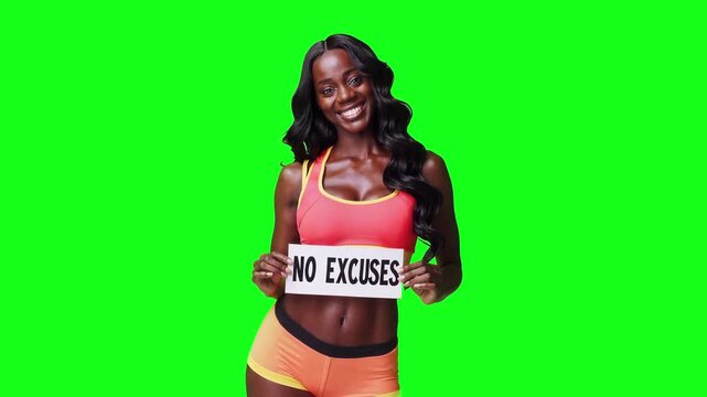 Realistic video of a happy fitness model with dark skin and long wavy black hair wearing a pink sports bra, holding a sign that says &ldquo;No Excuses&rdquo;, smiling at the camera and isolated on a bright green 