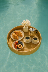 A tray of food and drinks is floating in a pool